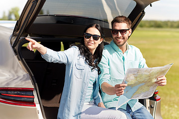 Image showing happy man and woman with road map at hatchback car