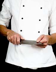 Image showing Professional chef holding a sharp cooking knife in hands wearing
