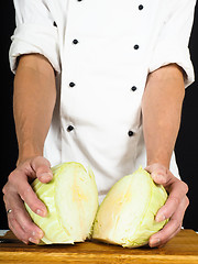 Image showing Professional chef showing a cabbage cut into two pieces on a woo