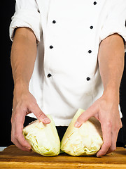 Image showing Professional chef showing a cabbage cut into two pieces on a woo
