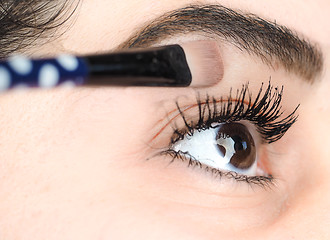 Image showing Female lying final touch of makeup at extreme closeup