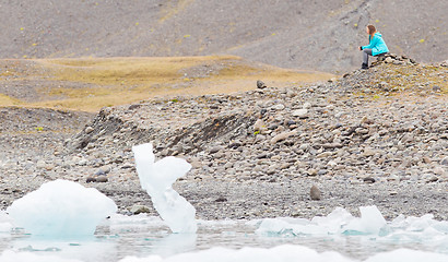 Image showing Woman sitting on the beach at Jokulsarlon glacier lagoon - Icela