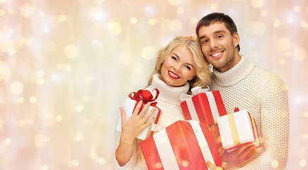 Image showing happy couple in sweaters holding christmas gifts