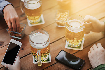 Image showing close up of hands with smartphones and beer at bar