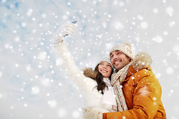 Image showing happy couple taking selfie by smartphone in winter