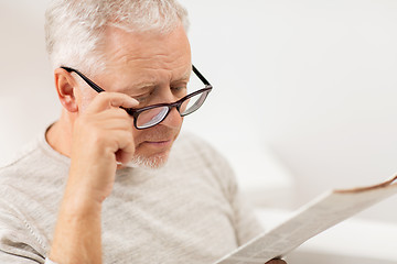 Image showing close up of old man in glasses reading newspaper