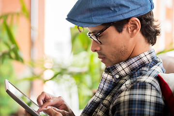 Image showing close up of man with tablet pc sitting at cafe