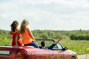 Image showing happy friends driving in cabriolet car at country