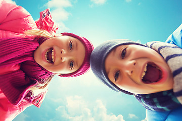 Image showing happy little boy and girl faces over blue sky