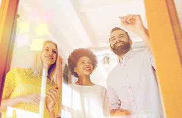 Image showing happy creative team writing on stickers at office