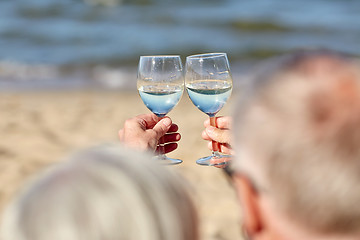 Image showing happy senior couple drinking wine on summer beach