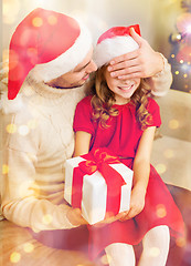 Image showing smiling father surprises daughter with gift box