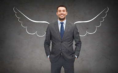 Image showing happy businessman with angel wings over gray