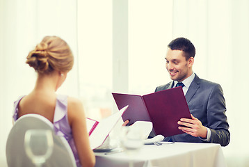 Image showing smiling young man looking at menu at restaurant