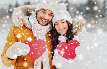 Image showing happy couple with red hearts over winter landscape