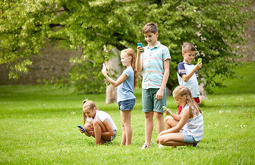 Image showing kids with smartphones playing game in summer park