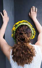 Image showing Woman stretching against a grey wall with a flower wreath in bea