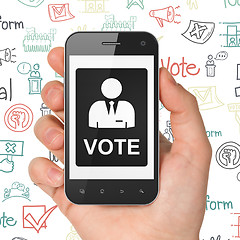 Image showing Political concept: Hand Holding Smartphone with Ballot on display