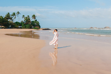 Image showing Woman legs walking on the beach sand