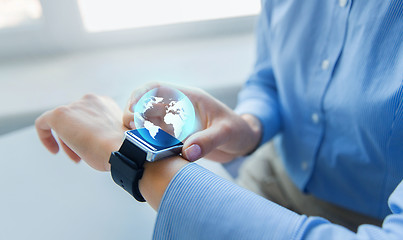 Image showing close up of hands and globe hologram on smartwatch