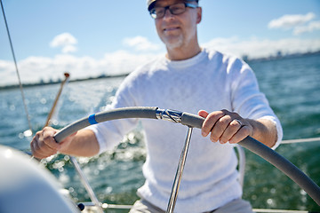 Image showing senior man at helm on boat or yacht sailing in sea