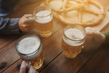 Image showing close up of hands with beer mugs at bar or pub