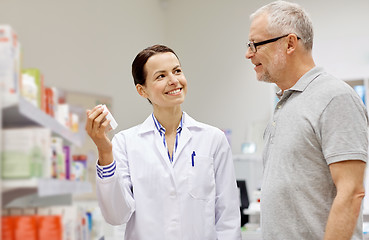 Image showing pharmacist showing drug to senior man at pharmacy