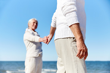 Image showing close up of senior couple holding hands on beach