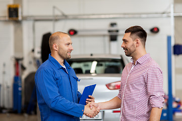 Image showing auto mechanic and man shaking hands at car shop