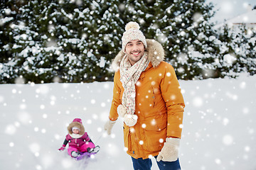 Image showing happy man carrying little kid on sled in winter