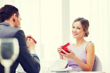 Image showing excited young woman looking at boyfriend with box