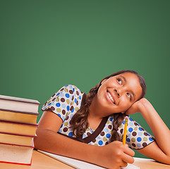 Image showing Cute Hispanic Girl Studying Looking Up to Blank Chalk Board