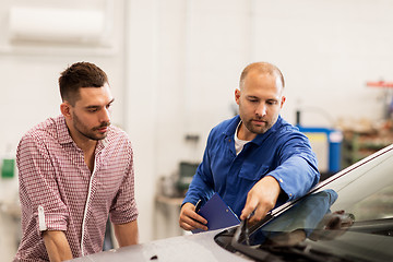 Image showing auto mechanic with clipboard and man at car shop