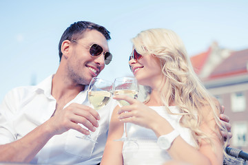 Image showing smiling couple in sunglasses drinking wine in cafe