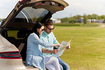 Image showing happy man and woman with road map at hatchback car