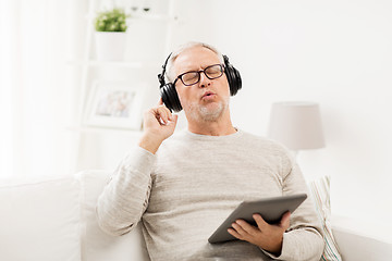 Image showing senior man with tablet pc and headphones at home