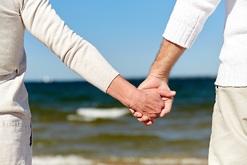 Image showing close up of senior couple holding hands on beach