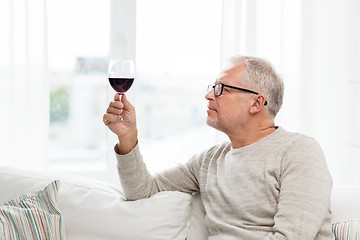 Image showing senior man drinking red wine from glass at home