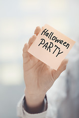 Image showing Woman holding adhesive note with Halloween party text