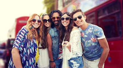 Image showing smiling hippie friends with selfie stick in london