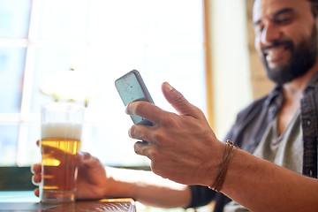 Image showing close up of man with smartphone and beer at pub