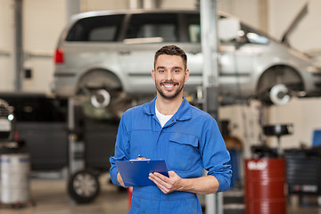 Image showing happy mechanic man with clipboard at car workshop