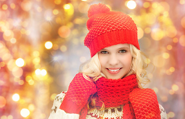 Image showing happy woman in hat, scarf and mittens over lights