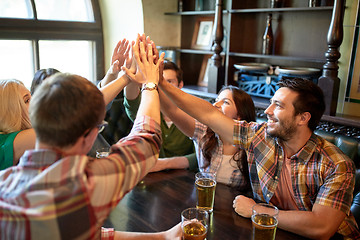 Image showing friends with beer making high five at bar or pub