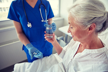 Image showing nurse giving medicine to senior woman at hospital