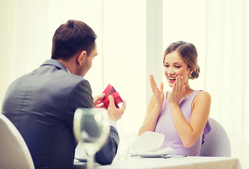 Image showing excited young woman looking at boyfriend with box