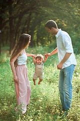 Image showing Young beautiful father, mother and little toddler son against green trees