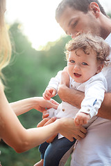 Image showing Young beautiful father, mother and little toddler son against green trees