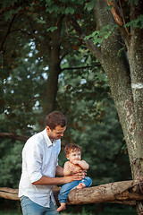 Image showing Young beautiful father and little toddler son against green trees