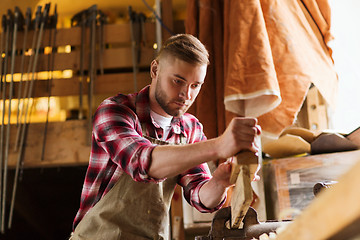 Image showing carpenter working with plane and wood at workshop